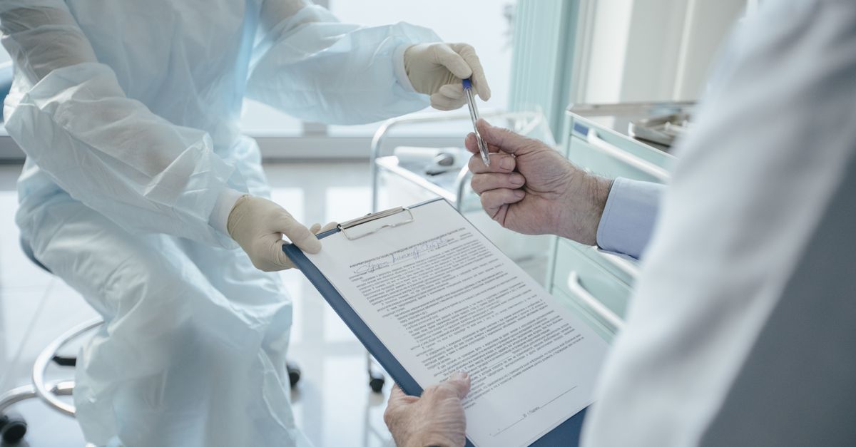 A clinician handing a patient a clipboard to sign — the kind of PHI handling a business associate agreement governs.