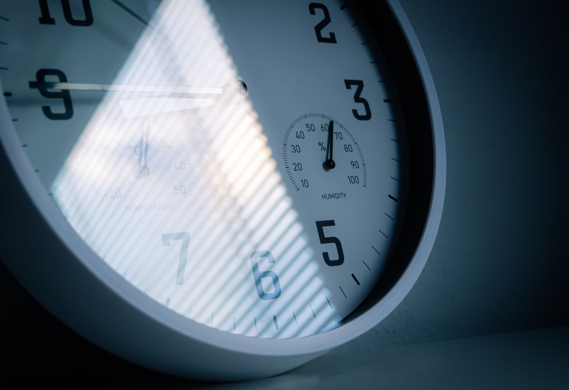 Close-up of a wall clock with light from window blinds falling across its face, the observation window at the centre of a SOC 2 Type 2 timeline.